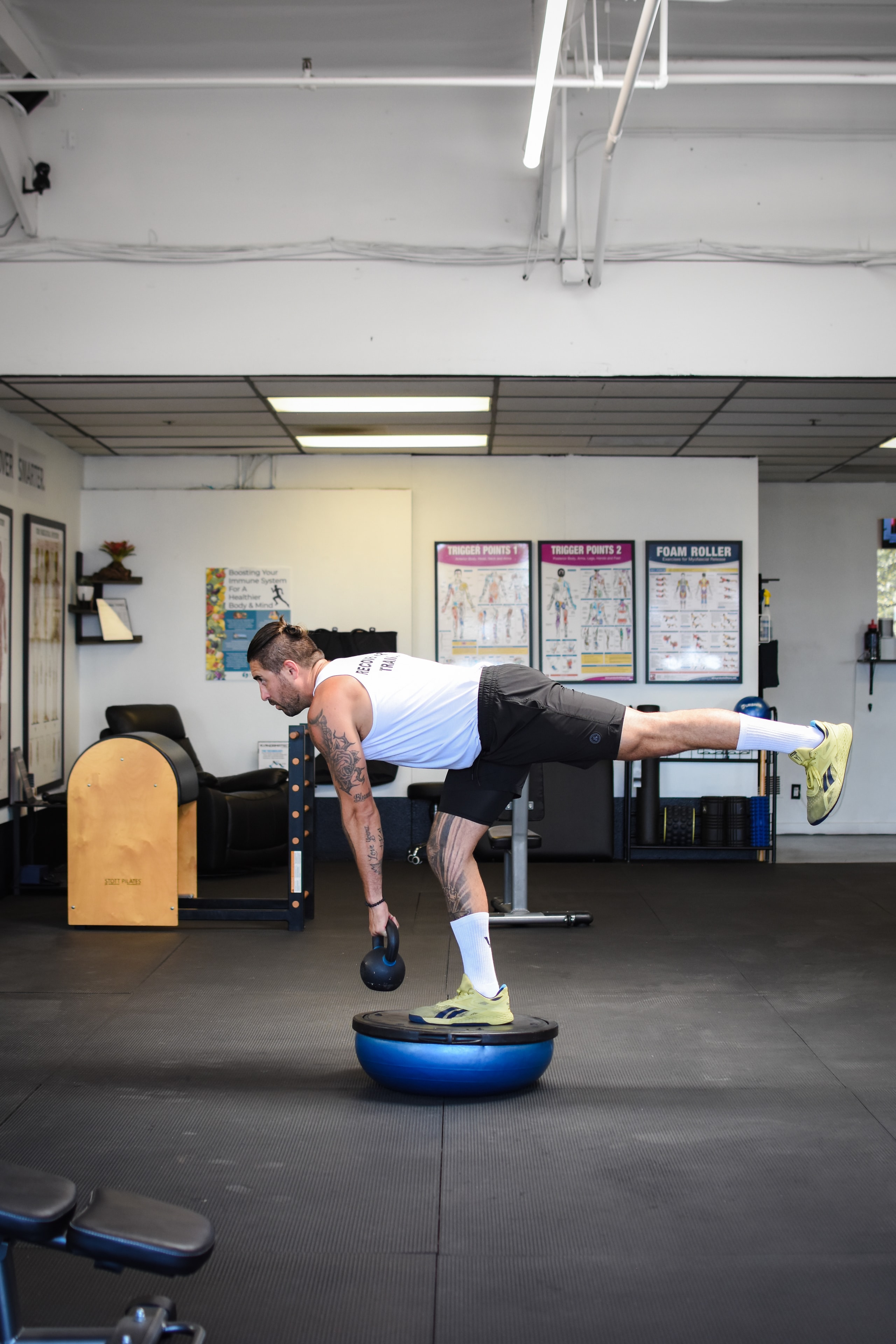 Trainer balancing on bosu ball with kettlebell demonstrating functional training science at Symmetry Fitness
