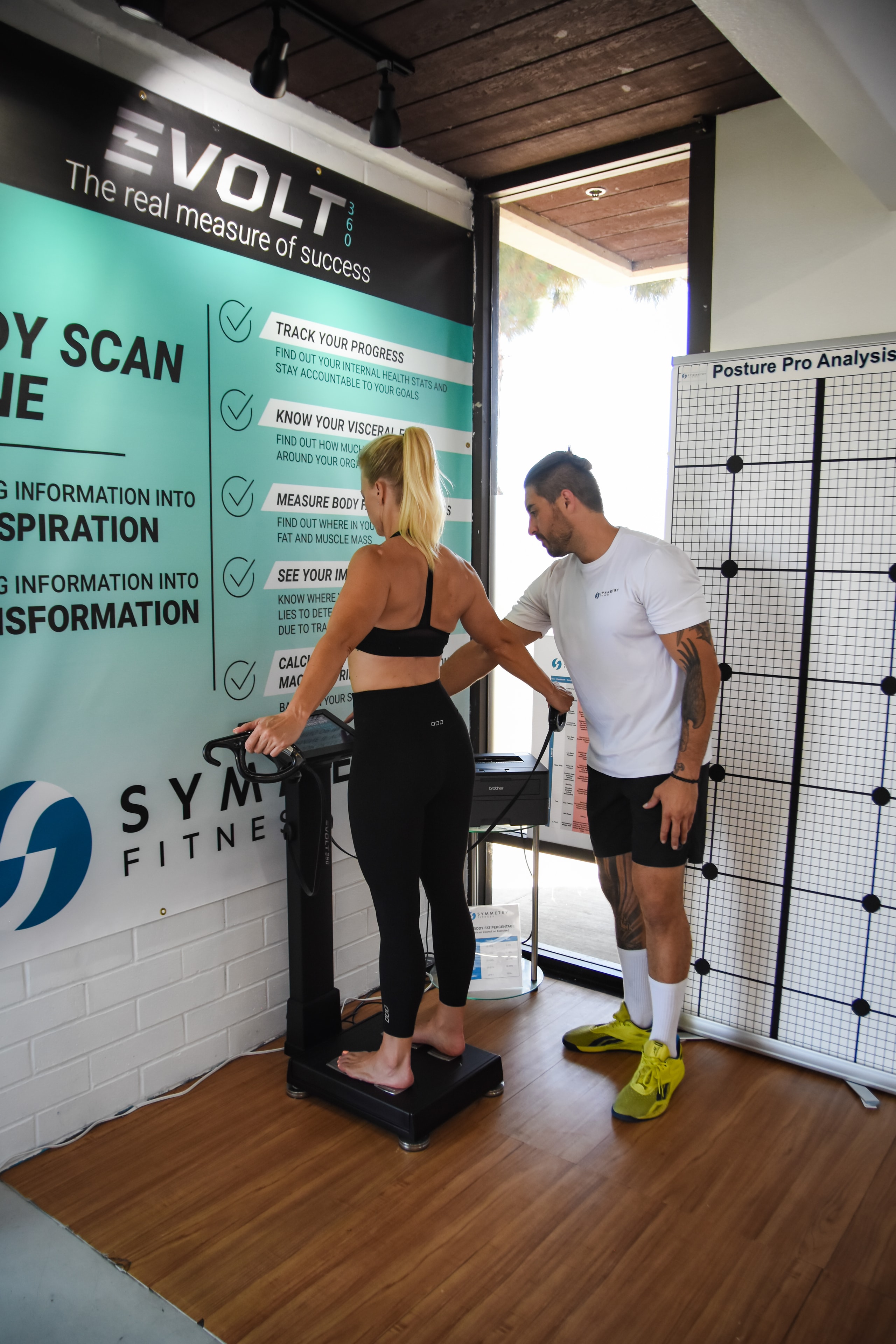 Trainer conducting an InBody body composition scan with client at Symmetry Fitness