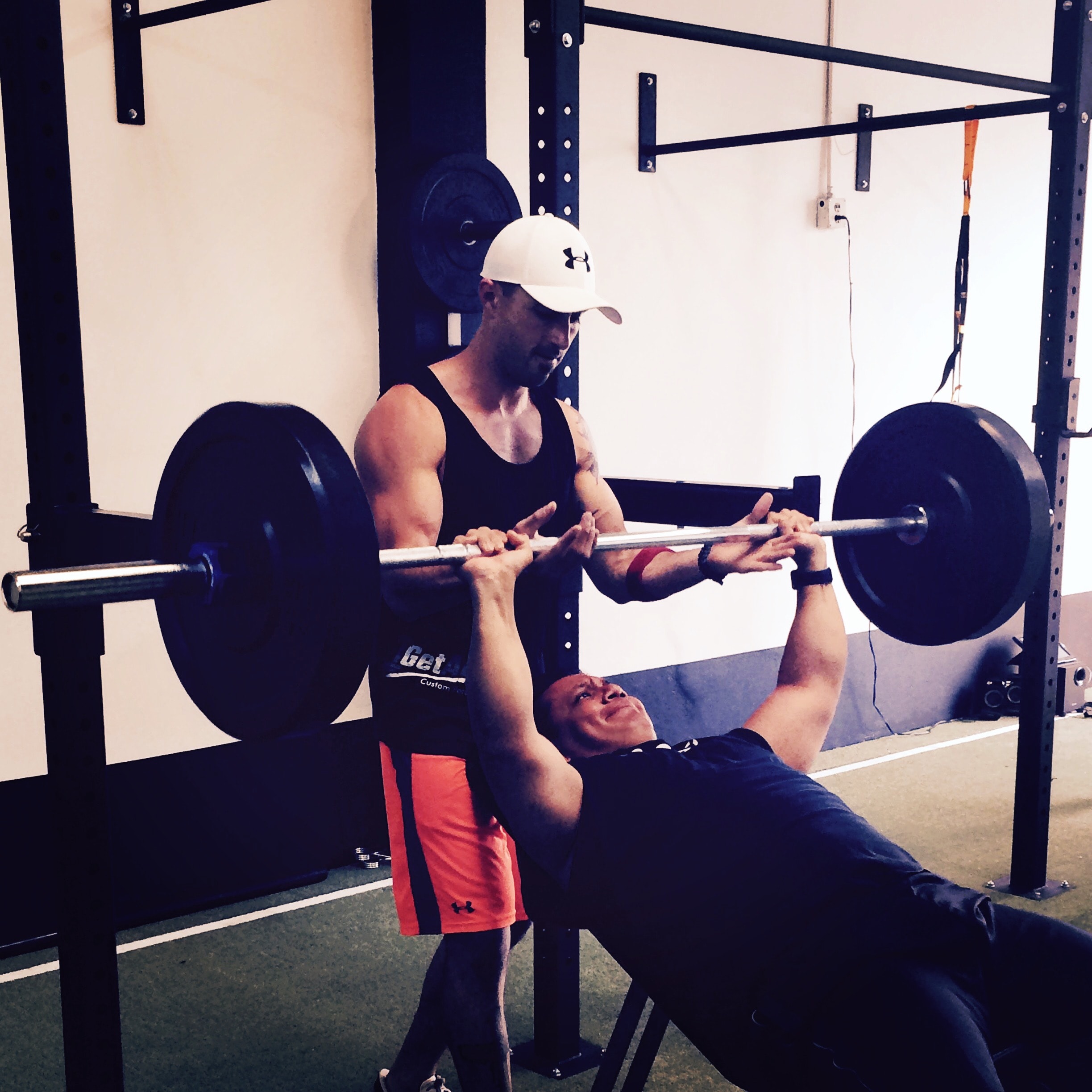 Trainer spotting client on bench press during a private one-on-one strength training session